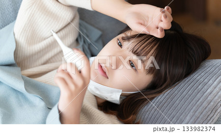熱を測る体調不良の女性 133982374