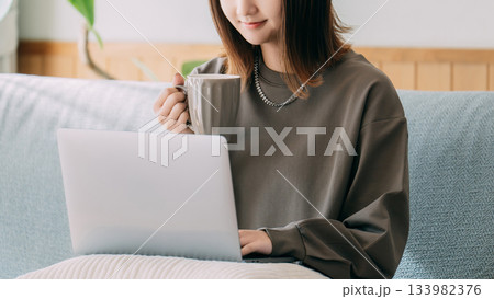 ソファに座ってパソコンを使う女性 133982376