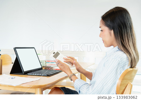 Professional woman calculating finance using calculator and tablet 133983062