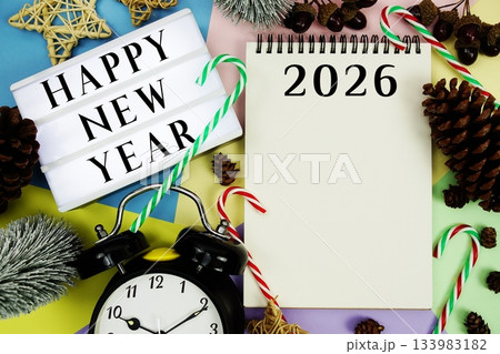 Happy New Year 2026 text with alarm clock and christmas decoration on pastel background Happy New Year 2026 text with alarm clock and christmas decoration on pastel background 133983182