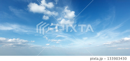 Bright blue sky with fluffy clouds on a sunny day creating a serene atmosphere Bright blue sky with fluffy clouds on a sunny day creating a serene atmosphere 133983430