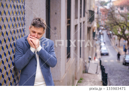 Man plays harmonica outdoors in city street Man plays harmonica outdoors in city street 133983471