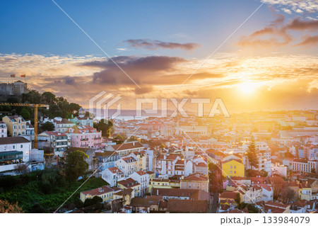 Breathtaking sunset over Lisbon, highlighting the city's rooftops, Carmo Convent ruins, and the iconic 25th of April Bridge. Portugal 133984079