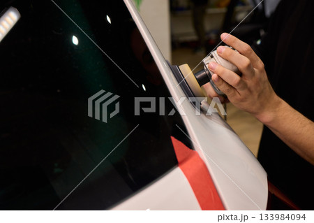 Polishing black car surface thoroughly, Detailed buffing to achieve showroom quality shine, Expert technician uses orbital buffer and foam pad to enhance vehicle gloss Polishing black car surface thoroughly, Detailed buffing to achieve showroom quality shine, Expert technician uses orbital buffer and foam pad to enhance vehicle gloss 133984094
