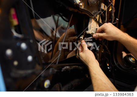 Mechanic fixing vehicle door parts, Closeup of technician repairing car interior components, Professional worker servicing vehicle door with detailed focus and tools 133984363