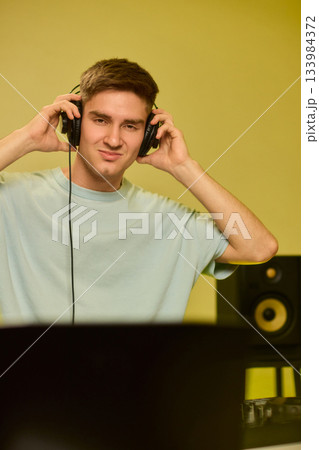 Youthful technician editing sound, Youthful sound engineer meticulously adjusting mixing console within modern streaming design setting to create perfect audio balance 133984372