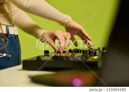 DJ setup overview, Energetic club DJ performing with digital controller in action, Content creator mixing music live using digital turntables under vibrant stage lights 133984380