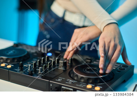DJ setup overview, Energetic club DJ performing with digital controller in action, Content creator mixing music live using digital turntables under vibrant stage lights 133984384