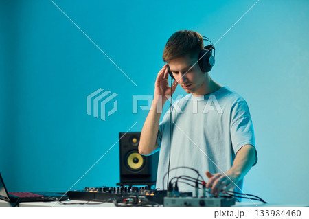 Youthful technician editing sound, Youthful sound engineer meticulously adjusting mixing console within modern streaming design setting to create perfect audio balance 133984460