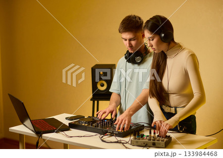 Music creators in studio, Studio session featuring musical synthesis and focused teamwork, Electronic music producers working together with various tools and instruments 133984468