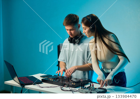 Music creators in studio, Studio session featuring musical synthesis and focused teamwork, Electronic music producers working together with various tools and instruments 133984470