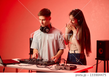 Music creators in studio, Studio session featuring musical synthesis and focused teamwork, Electronic music producers working together with various tools and instruments 133984475