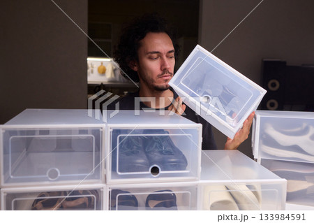 Organizing clear shoe containers effectively, Arranging transparent footwear storage with focus and style, Meticulous placement of feedthrough shoe boxes in minimalist 133984591