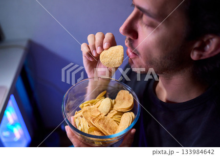 Programmer enjoying late night snack, Individual working alone in home office environment, Solitary male professional grubbing on sandwich during late hours at his desk 133984642