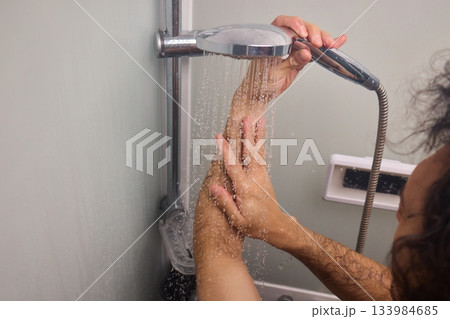 Close view of man washing hair thoroughly, Man under shower rinses hair closely while grooming himself, Detailed shot of man cleansing his hair with water under shower 133984685