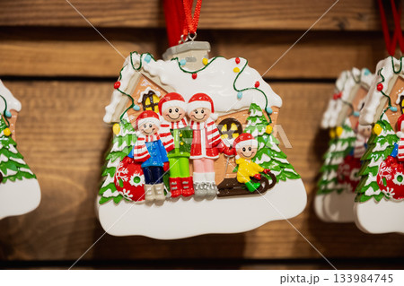 Close up of gingerbread style family Christmas ornament hanging on wooden display, colorful holiday decoration at festive market in kiosk. 133984745