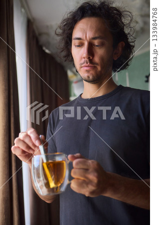 Warm tea preparation, Relaxed moment with steaming hot beverage in tranquility, Quiet domestic setting emphasizing mindful hand movements during tea stirring activities 133984768