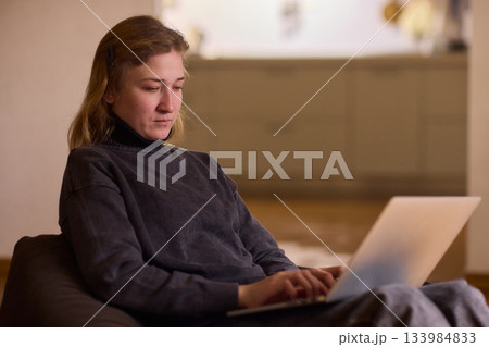 Determined individual with cerebral palsy immersed in educational activities indoors, Courageous woman with cerebral palsy concentrates on studying at home with dedication 133984833