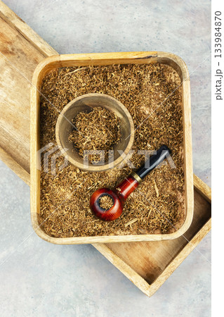 Smoking pipe with tobacco on a table. 133984870