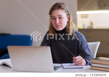 Determined individual with cerebral palsy immersed in educational activities indoors, Courageous woman with cerebral palsy concentrates on studying at home with dedication 133984876