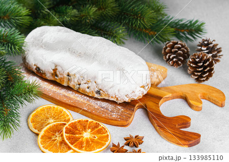 Traditional Christmas Stollen, sweet fruit loaf with sugar icing on wooden board and festive decor Traditional Christmas Stollen, sweet fruit loaf with sugar icing on wooden board and festive decor 133985110