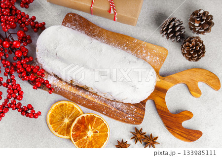 Traditional Christmas Stollen, sweet fruit loaf with sugar icing on wooden board and festive decor Traditional Christmas Stollen, sweet fruit loaf with sugar icing on wooden board and festive decor 133985111