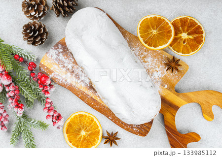 Traditional Christmas Stollen, sweet fruit loaf with sugar icing on wooden board and festive decor Traditional Christmas Stollen, sweet fruit loaf with sugar icing on wooden board and festive decor 133985112