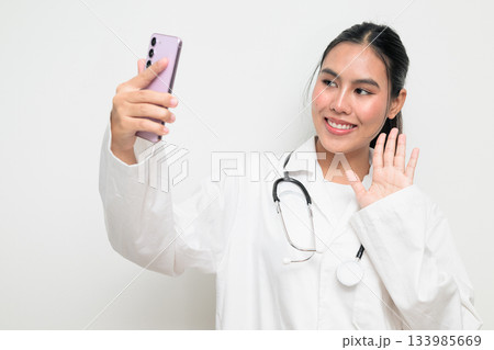 Woman Doctor with Stethoscope in White Uniform on Plain Background Using Phone Taking Selfie Woman Doctor with Stethoscope in White Uniform on Plain Background Using Phone Taking Selfie 133985669