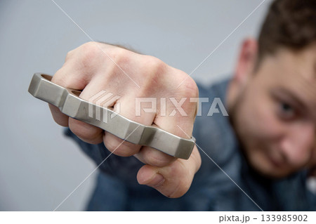 A man strikes a brass knuckles on a light background, a street gang of hooligans A man strikes a brass knuckles on a light background, a street gang of hooligans 133985902