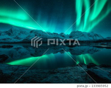 Aurora borealis over the snowy mountains, reflection in water 133985952