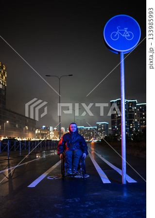 Motivated man with disability in wheelchair in rgb neon light on night walk outdoors to keep active. Motivated man with disability in wheelchair in rgb neon light on night walk outdoors to keep active. 133985993