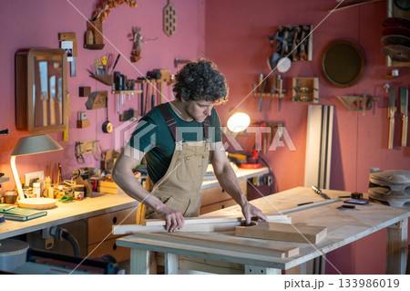 Man skilled carpenter creating unique furniture items for new work project in own carpentry workshop 133986019