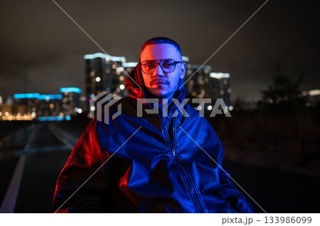 Portrait of thoughtful disabled man in wheelchair in blue red neon rgb light on late night walk. 133986099