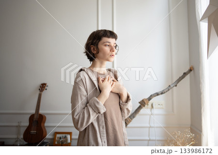 Calm young woman put hands on chest to guide deep breath and reflection, stress relief after panic 133986172