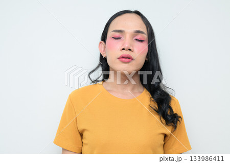Portrait of a young Thai transgender person against white background eyes closed 133986411