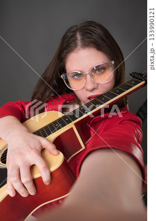 Female guitarist and vlogger for hype bites her guitar's neck and takes selfie during performance. This is an example of user generated content Female guitarist and vlogger for hype bites her guitar's neck and takes selfie during performance. This is an example of user generated content 133990121