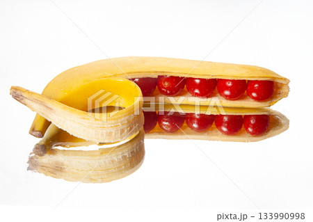 A peeled banana creatively sliced to reveal cherry tomatoes inside 133990998
