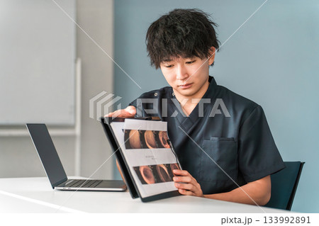 病院の診察で内視鏡写真を見せながら説明する男性医師 133992891