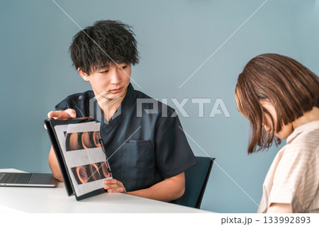 病院の診察で内視鏡写真を見せながら説明する男性医師 133992893
