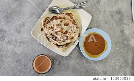 This is a group of food with Roti Canai, Teh Tarik and Curry 133993059