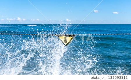強い波が打ち寄せる海と警告サイン、海難事故への注意喚起 133993511