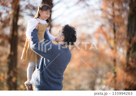 秋の紅葉の空の中で子どもを高い高いする父親 133994263