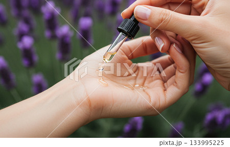 Close-up of Essential Oil Dropping onto Hand in Lavender Field 133995225