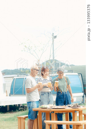 海辺で親子三人が立ち乾杯するシーン 133995376