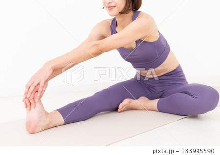 ストレッチ体操をするヨガウェア姿のミドル女性 ストレッチ体操をするヨガウェア姿のミドル女性 133995590