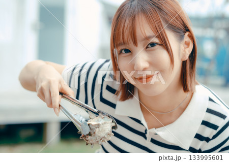 海辺で海鮮を焼く20代女性 133995601