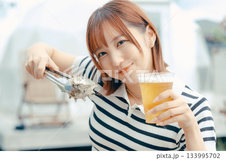 海鮮を焼きながらビールを楽しむ20代女性 海鮮を焼きながらビールを楽しむ20代女性 133995702