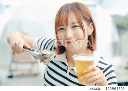 海鮮を焼きながらビールを楽しむ20代女性 海鮮を焼きながらビールを楽しむ20代女性 133995703