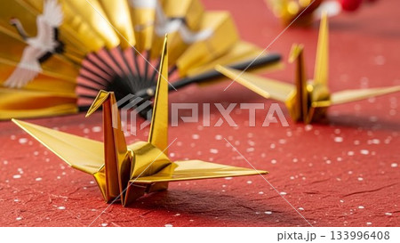 金色の扇子を背景にした金色の折り鶴の画像 133996408