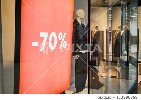 Store window display featuring discount sign and mannequin dressed in fashion 133996869